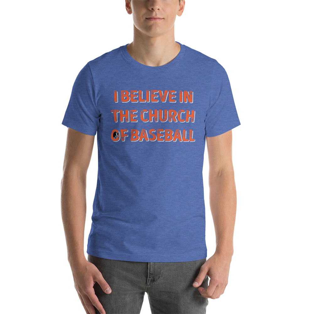 This image details the graphic design with the words "I believe in the church of baseball" with an image of a bull coming out of the O in "of". This shirt is an homage to the baseball movie Bull Durham featuring Kevin Costner and Susan Sarandon. This design is exclusive to Tailgate Mercantile and available only online. In this specific image, the shirt is being modelled on a young man.