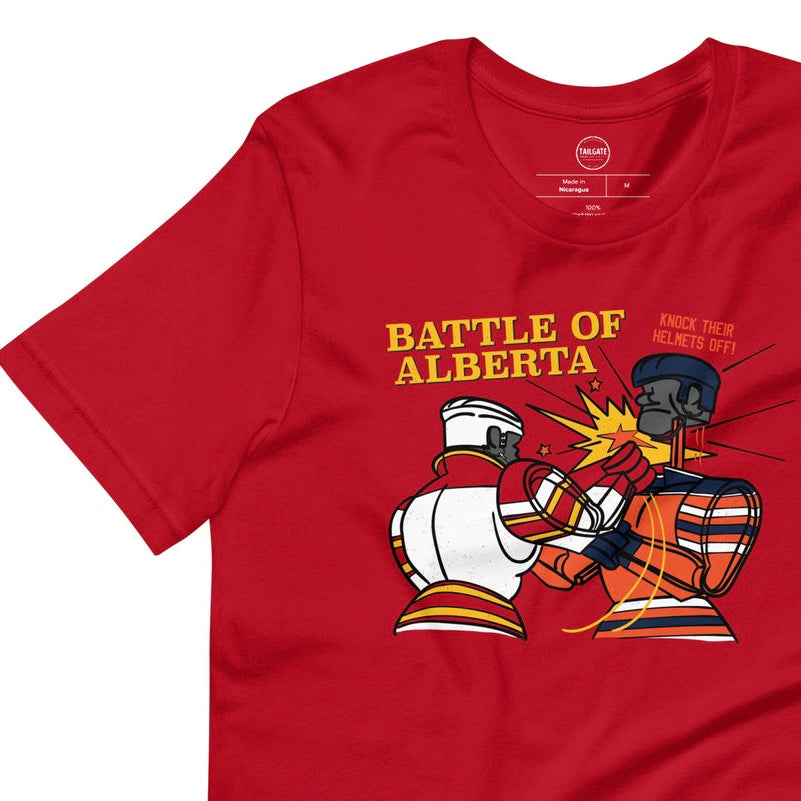 Image of red t-shirt with design of "Battle of Alberta" with rock'em, sock'em style hockey players fighting located on centre chest. Players in the design are completed in NHL Calgary Flames and Edmonton Oilers colours. This design is exclusive to Tailgate Mercantile and available only online.