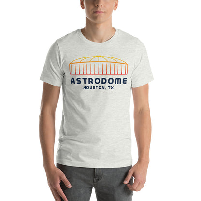 Image of man wearing heather ash t-shirt with design of "Astrodome, Houston, TX" illustrated ballpark completed in retro Houston Astros tequila sunrise colours located on centre chest. This design is exclusive to Tailgate Mercantile and available only online.