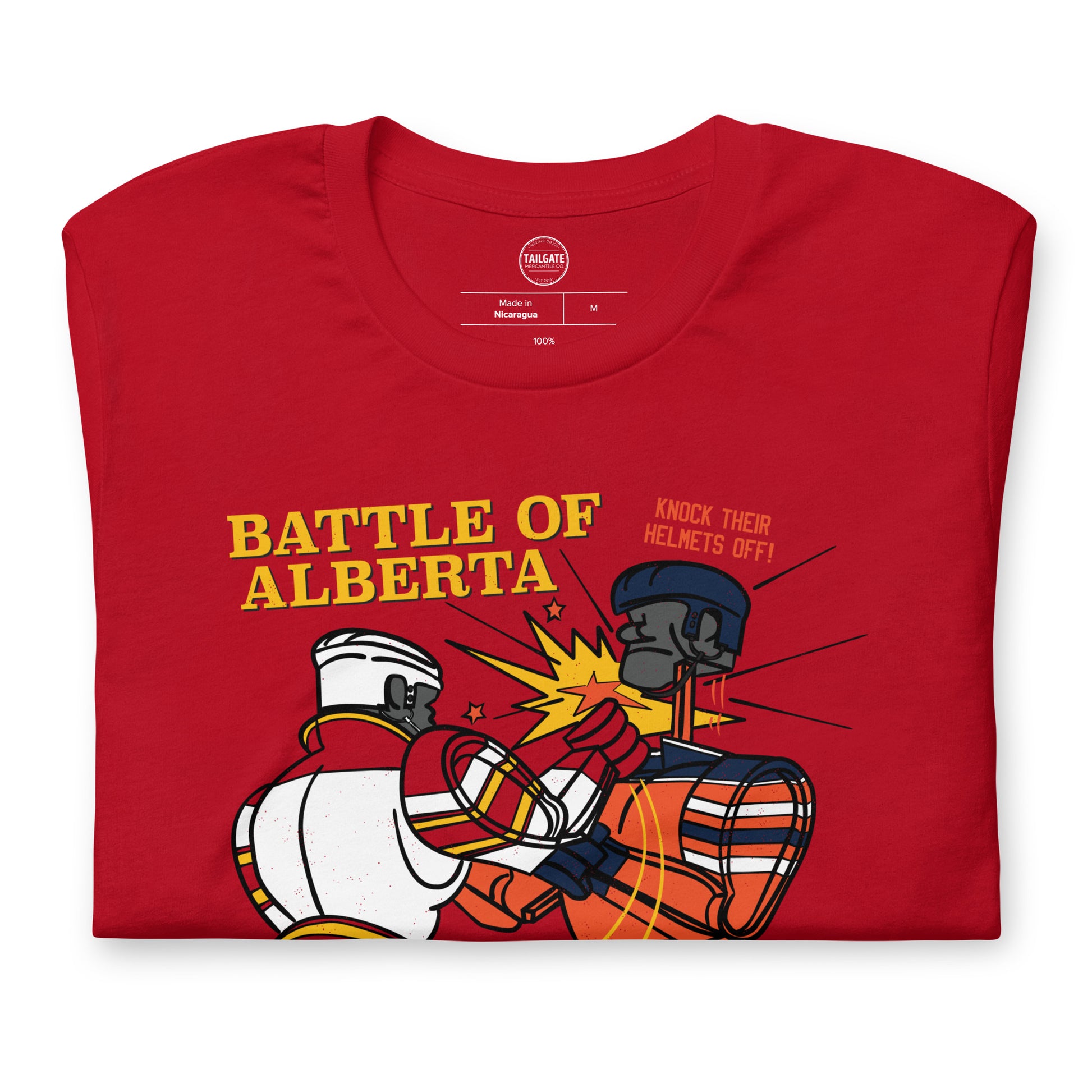 Close up image of red t-shirt with design of "Battle of Alberta" with rock'em, sock'em style hockey players fighting located on centre chest. Players in the design are completed in NHL Calgary Flames and Edmonton Oilers colours. This design is exclusive to Tailgate Mercantile and available only online.